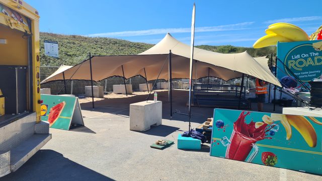 Outdoor stretch tent setup with concrete weights at beachside event location