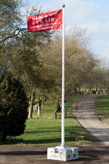 Flagpole with branded banner secured by concrete block weight