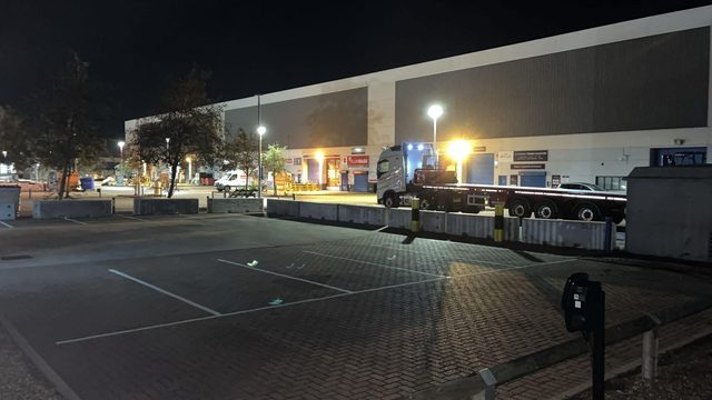 Concrete barrier blocks installed across a commercial car park at night