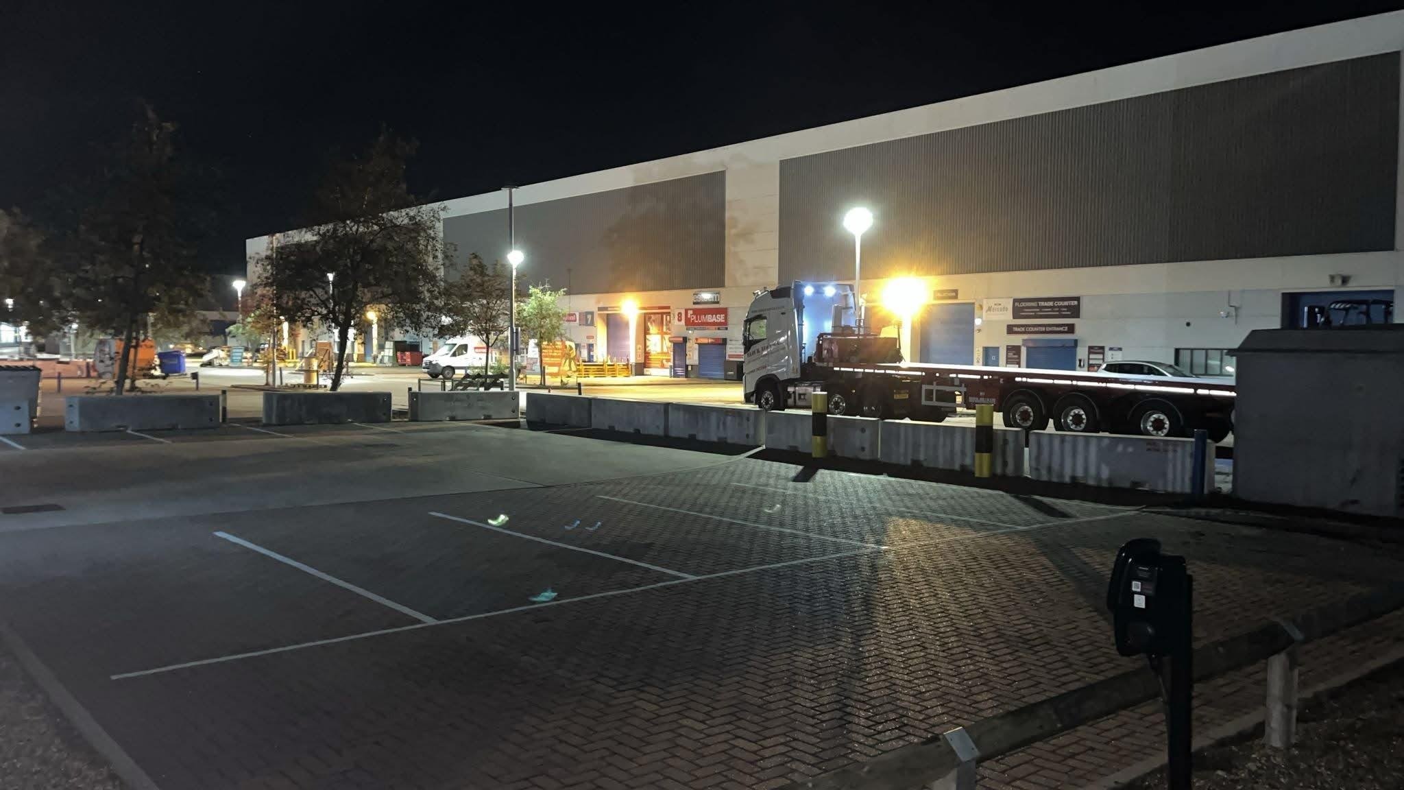 Concrete barrier blocks installed across a commercial car park at night