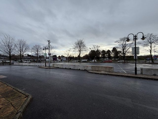 Concrete security barrier blocks positioned across an empty car park during the day